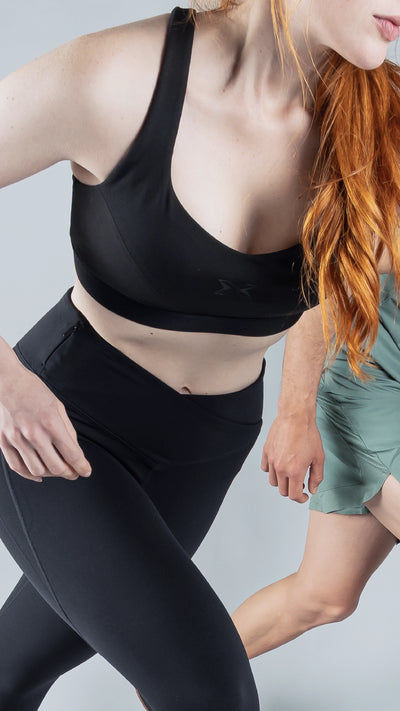 Torso de una mujer vestida con un top y mallas negras de deporte